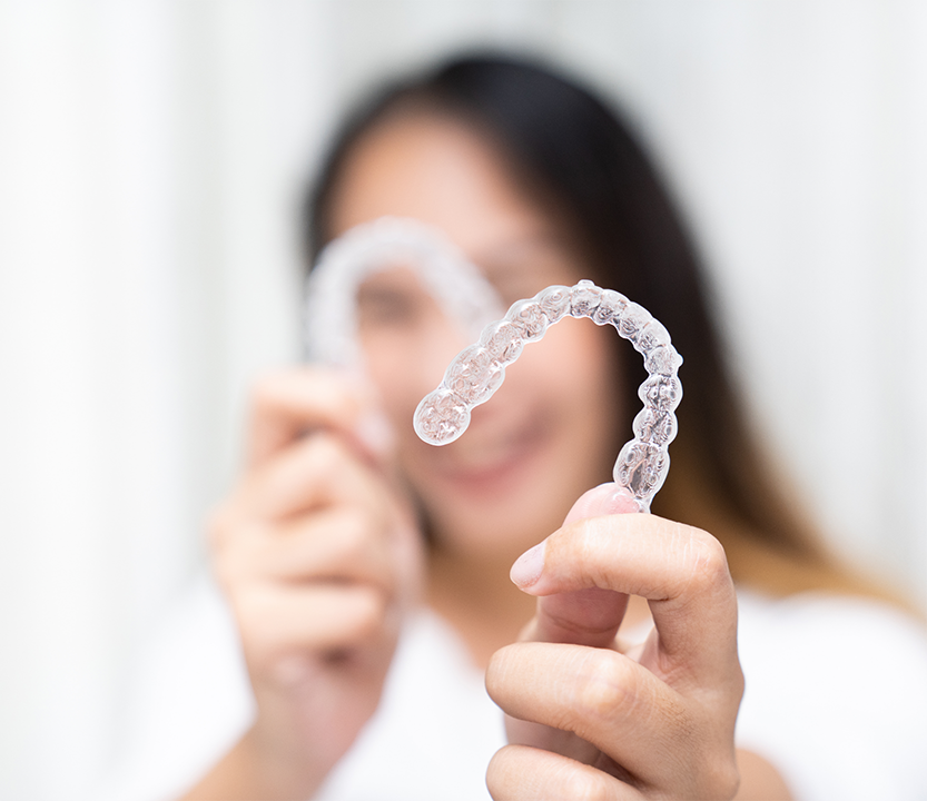 Woman making a heart shape with two clear aligners