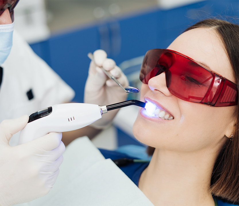 Dentist shining ultraviolet light on a patient's tooth