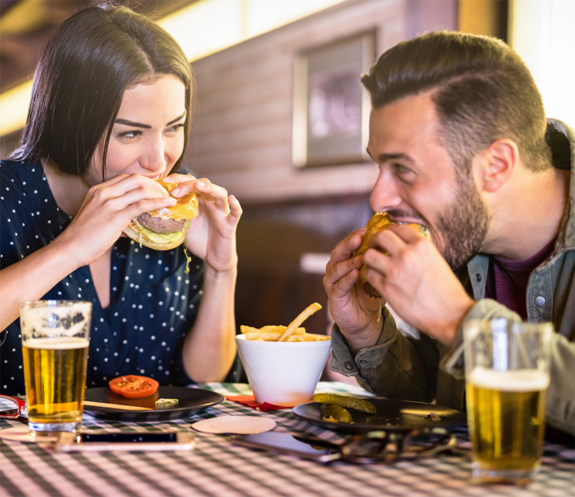 Man and woman eating burgers at a restaurant