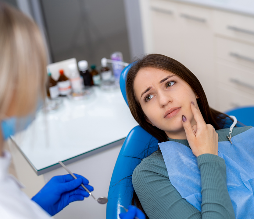 Woman at the dentist pointing to the side of her mouth that hurts