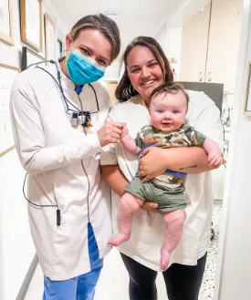 Dentist helping a mother make her baby wave at the camera