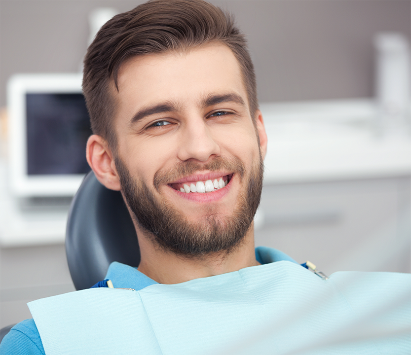 Young bearded man smiling at the dental office