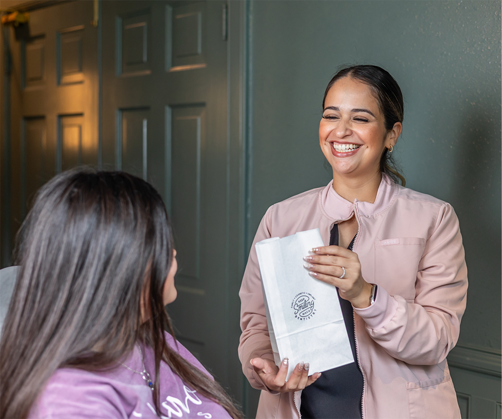 Dental team member handing a goodie bag to a patient