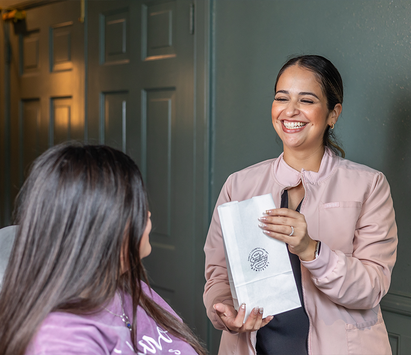 Dental team member handing a goodie bag to a patient